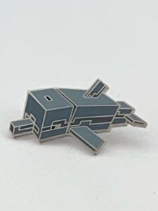 A photograph of a hard enamel pin in the shape of a cubist, stylized dolphin against a white background.